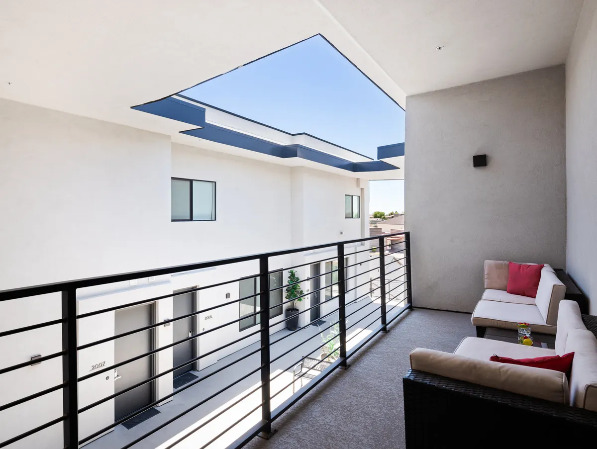 A private balcony with comfortable seating and a decorative plant overlooks the sky, inviting relaxation. The outdoor space is perfect for unwinding after a busy day, enjoying the view, or socializing.