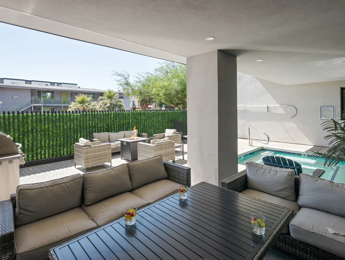 An inviting outdoor area showcases a comfortable seating arrangement next to a sparkling swimming pool, with greenery in the background. The space is ideal for relaxing, socializing, or enjoying a sunset after a day of exploring the city.