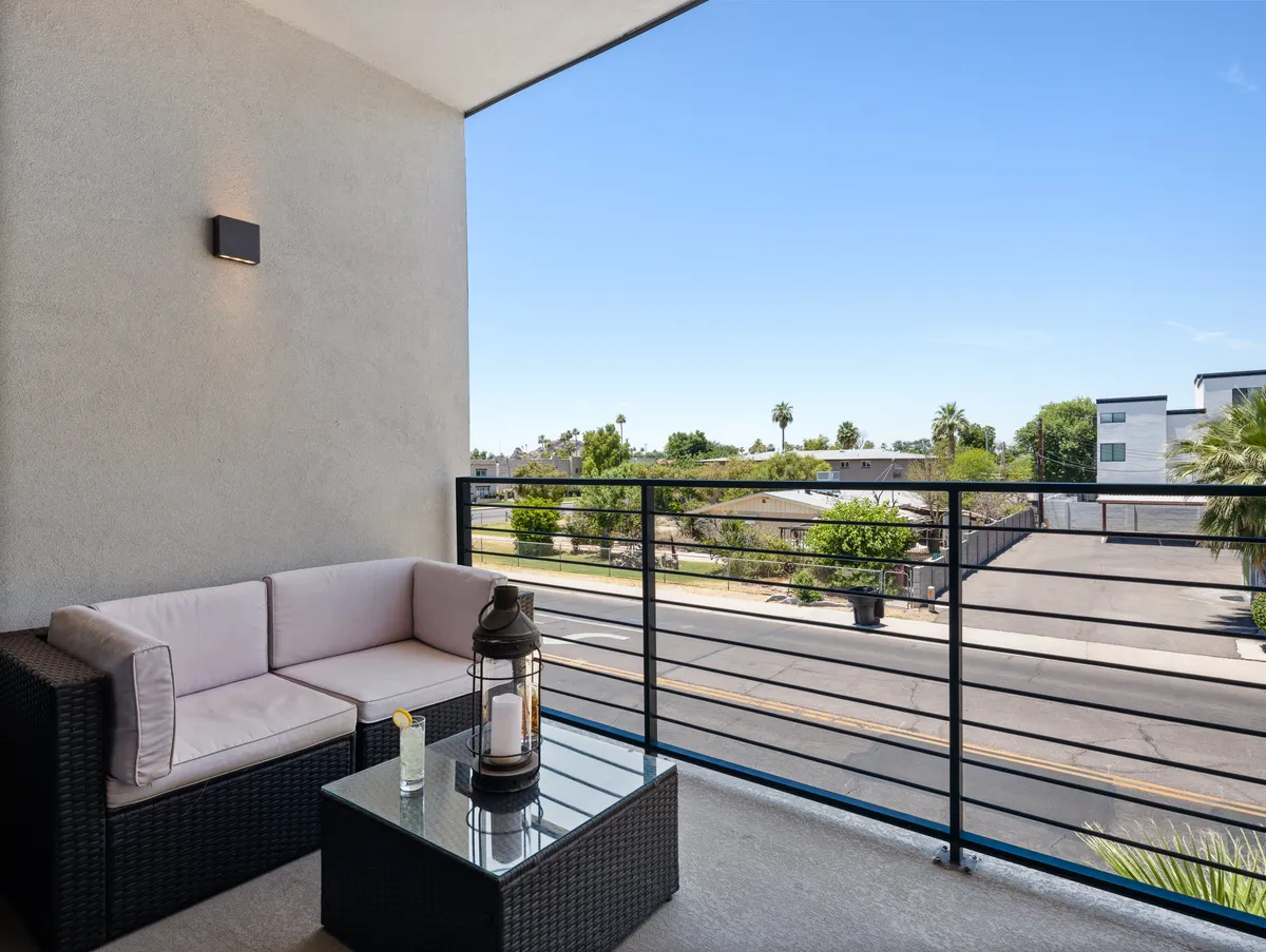 A private balcony overlooking the street, furnished with cozy seating and a coffee table. The scene invites relaxation, whether for morning coffee or evening cocktails, and connects the interior social space with the energetic ambiance of Old Town below.