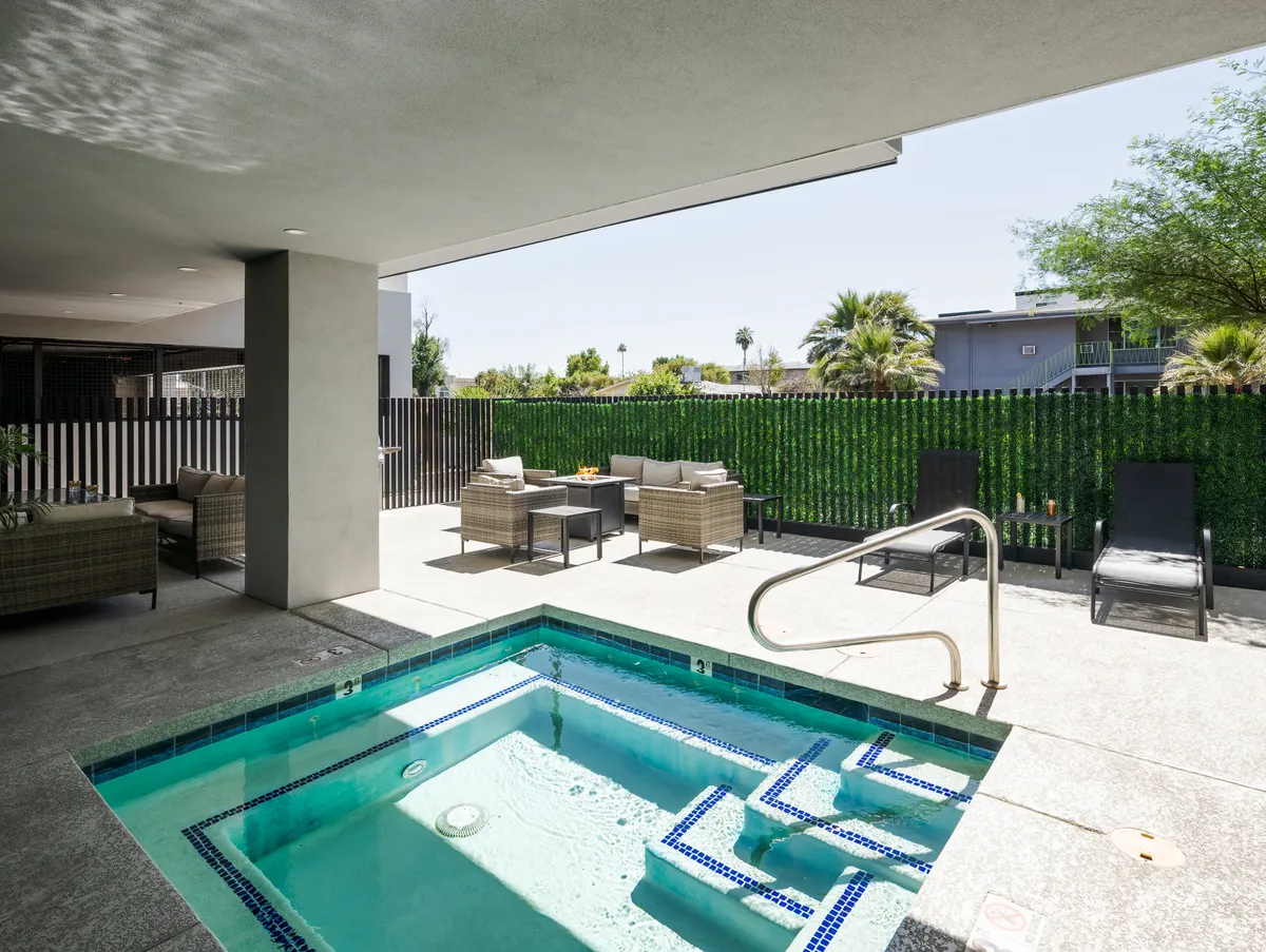 A serene outdoor pool area with inviting seating and lush greenery enclosed by a secure fence. The tranquil setting is ideal for sunbathing, swimming, or socializing, evoking a resort-like ambiance.